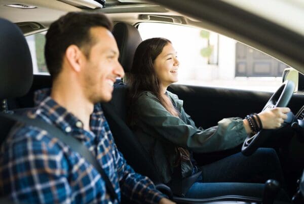 The Hanover SafeTeen Program - Happy and Smiling Dad With His Teenage Girl Practice Safe Driving Together in Preparation for Her Drivers License Test