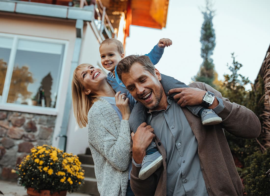 Personal Insurance - Happy Family Outside on a Beautiful Day Holding Their Son on Their Arms With a Smile